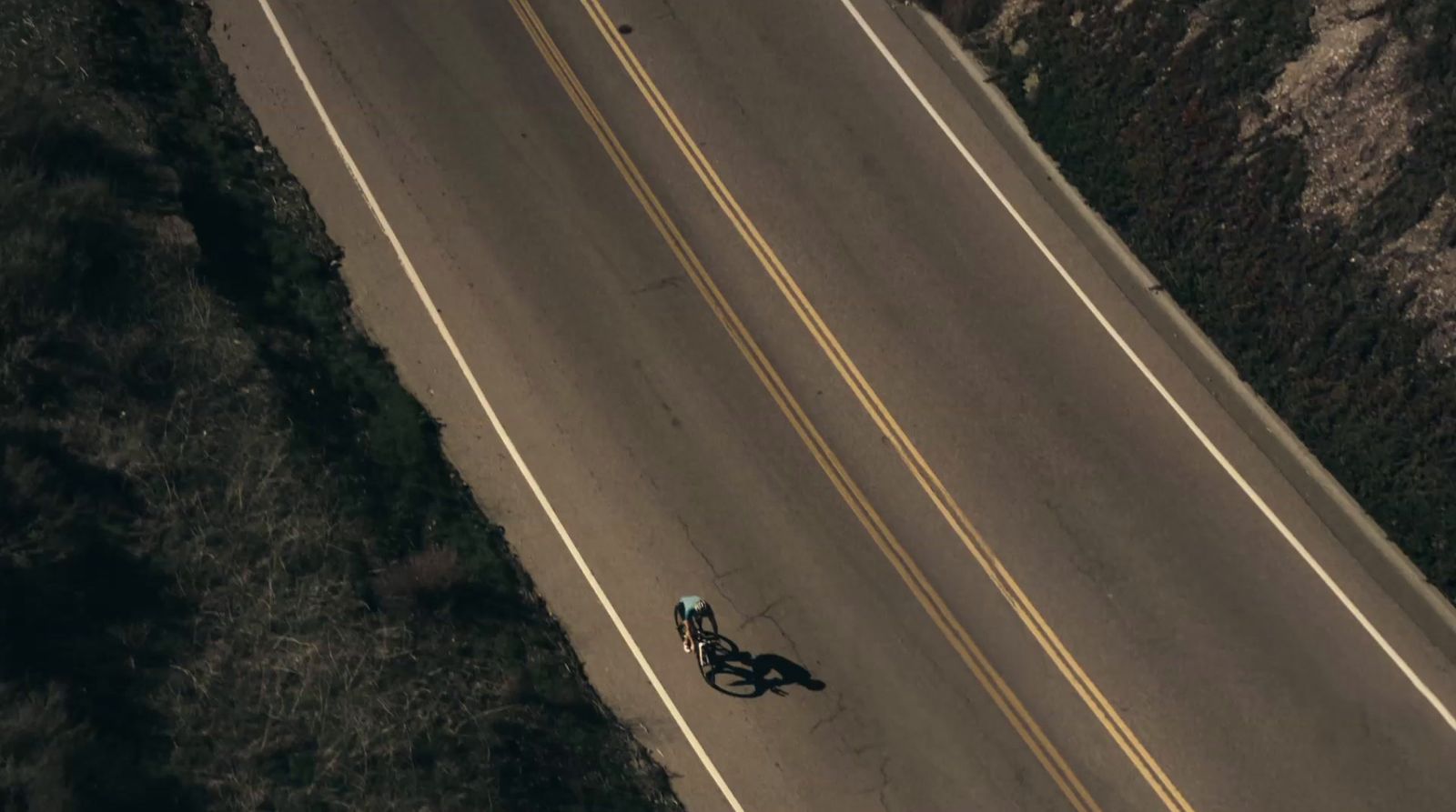 an aerial view of a motorcycle and a car on a road