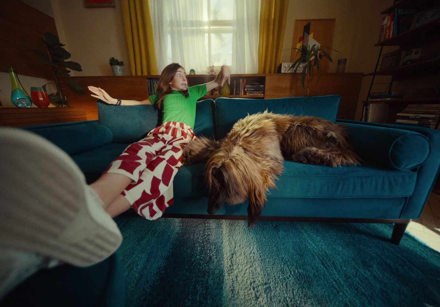 a woman sitting on a couch next to a dog