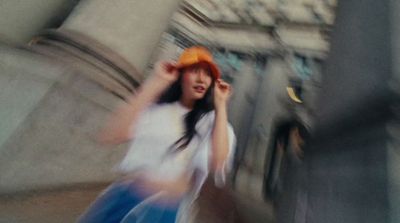 a woman walking down a street next to a tall building