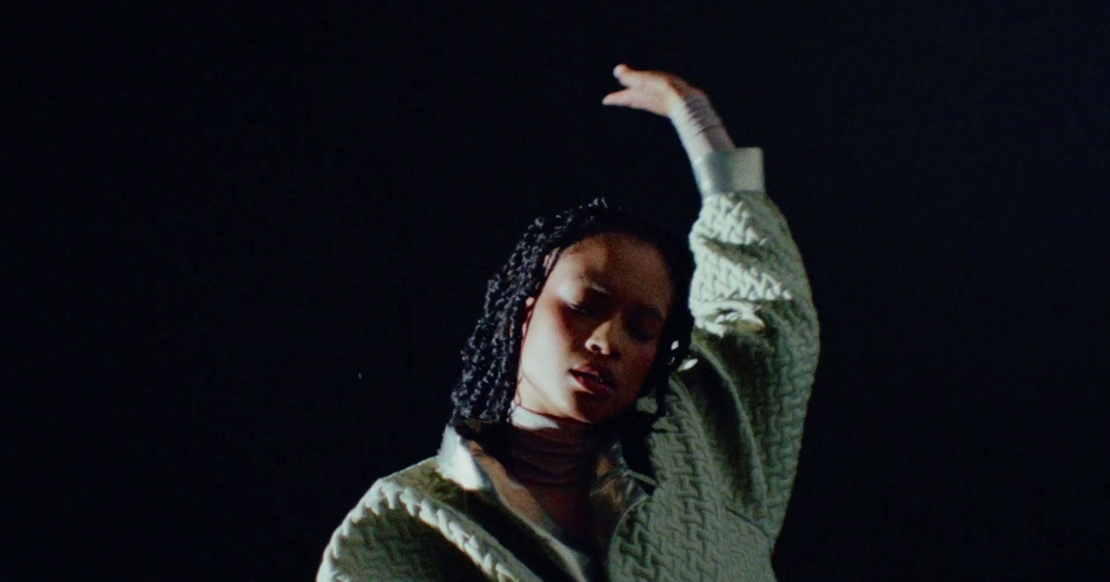 a woman with dreadlocks standing in the dark