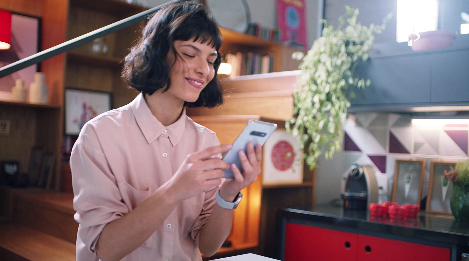 a woman in a pink shirt is looking at a cell phone