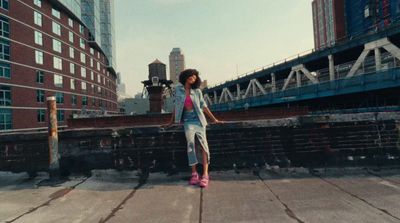 a woman standing on a sidewalk in front of a bridge