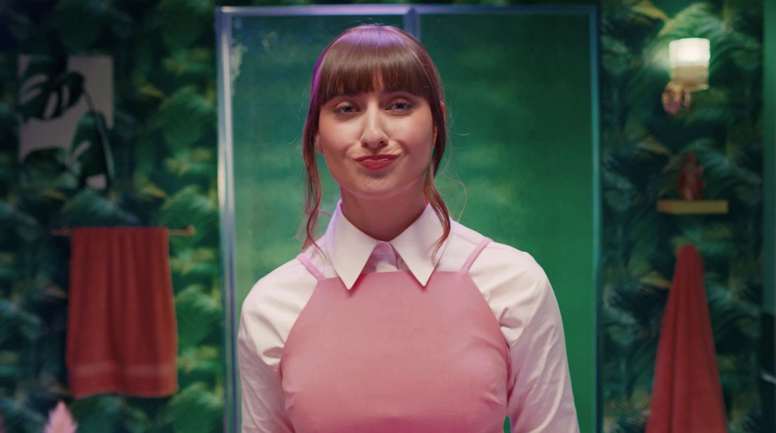 a woman in a pink apron standing in front of a mirror