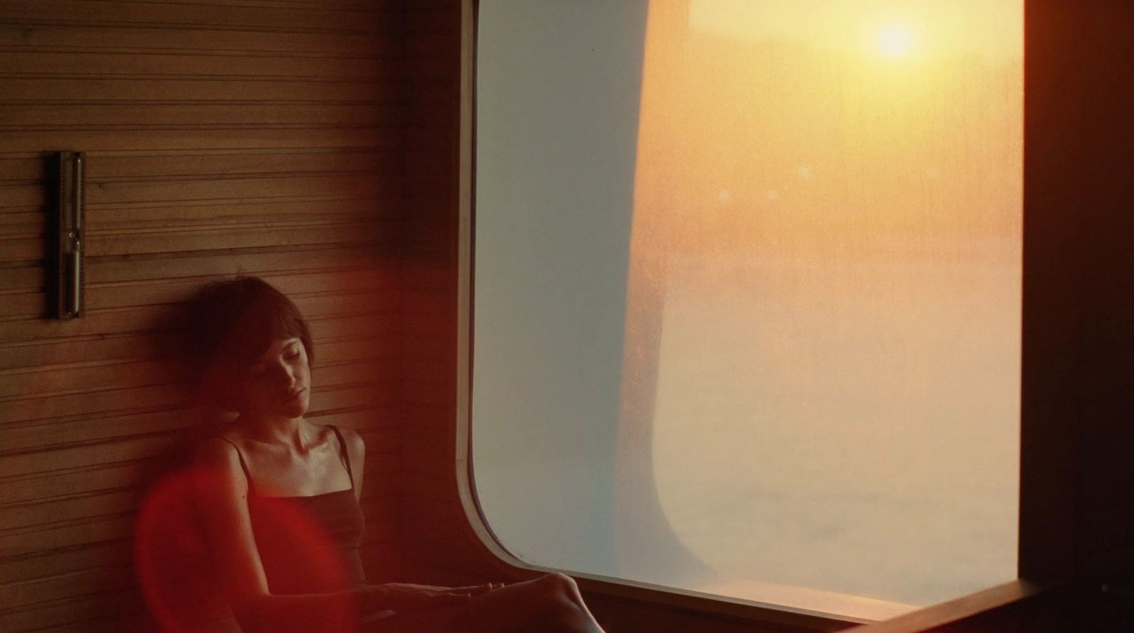 a woman in a red dress looking out a window