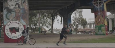 a man riding a bike down a sidewalk under a bridge