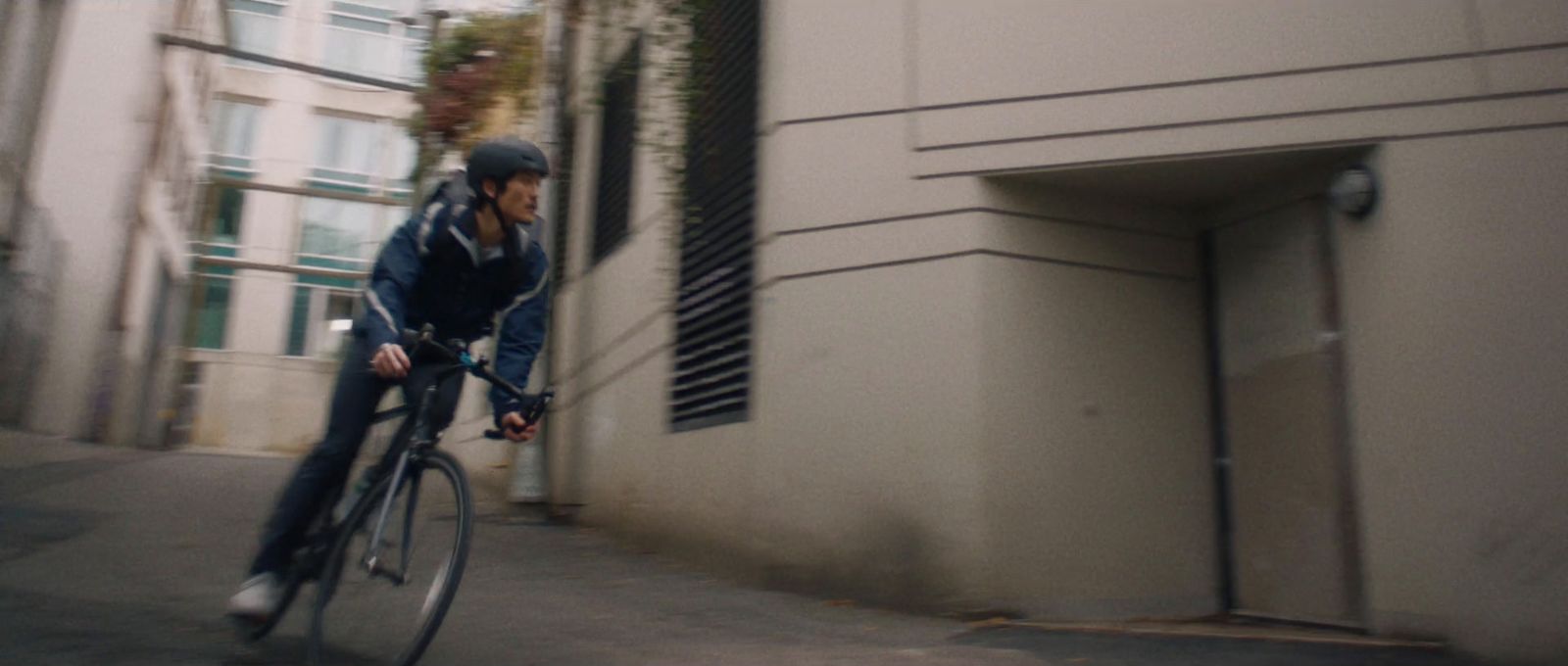 a man riding a bike down a street next to a tall building