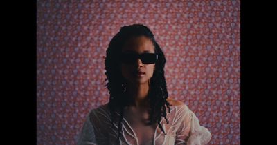 a woman wearing sunglasses standing in front of a wall