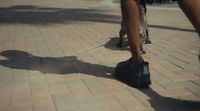 a person walking on a brick sidewalk with black shoes