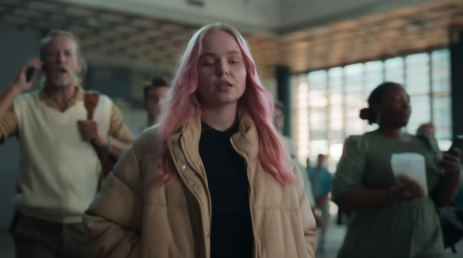 a woman with pink hair walking through a building