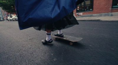 a person in a blue cape riding a skateboard