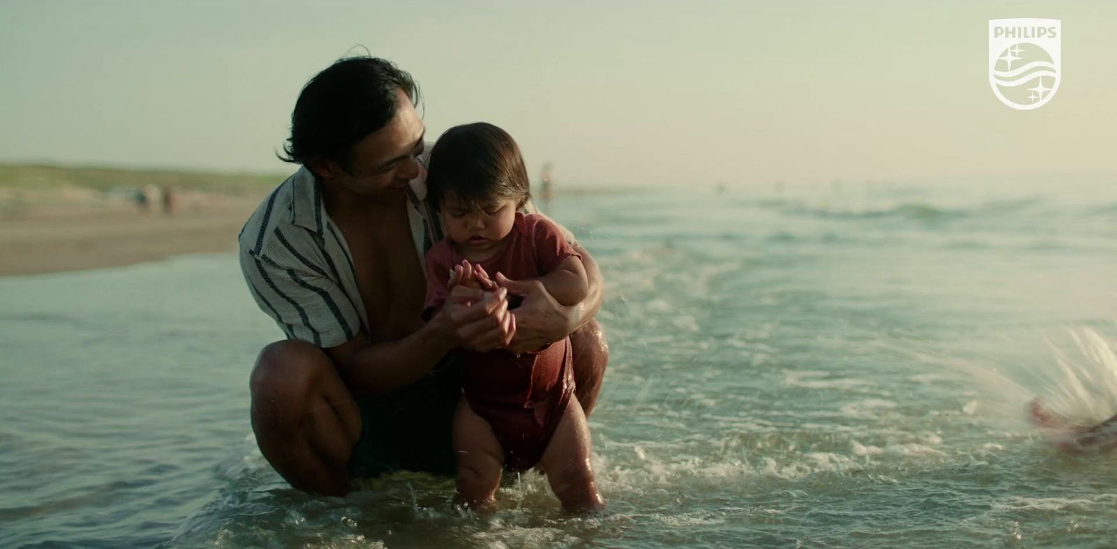 a man holding a small child in the ocean