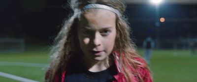 a young girl with long hair standing on a soccer field