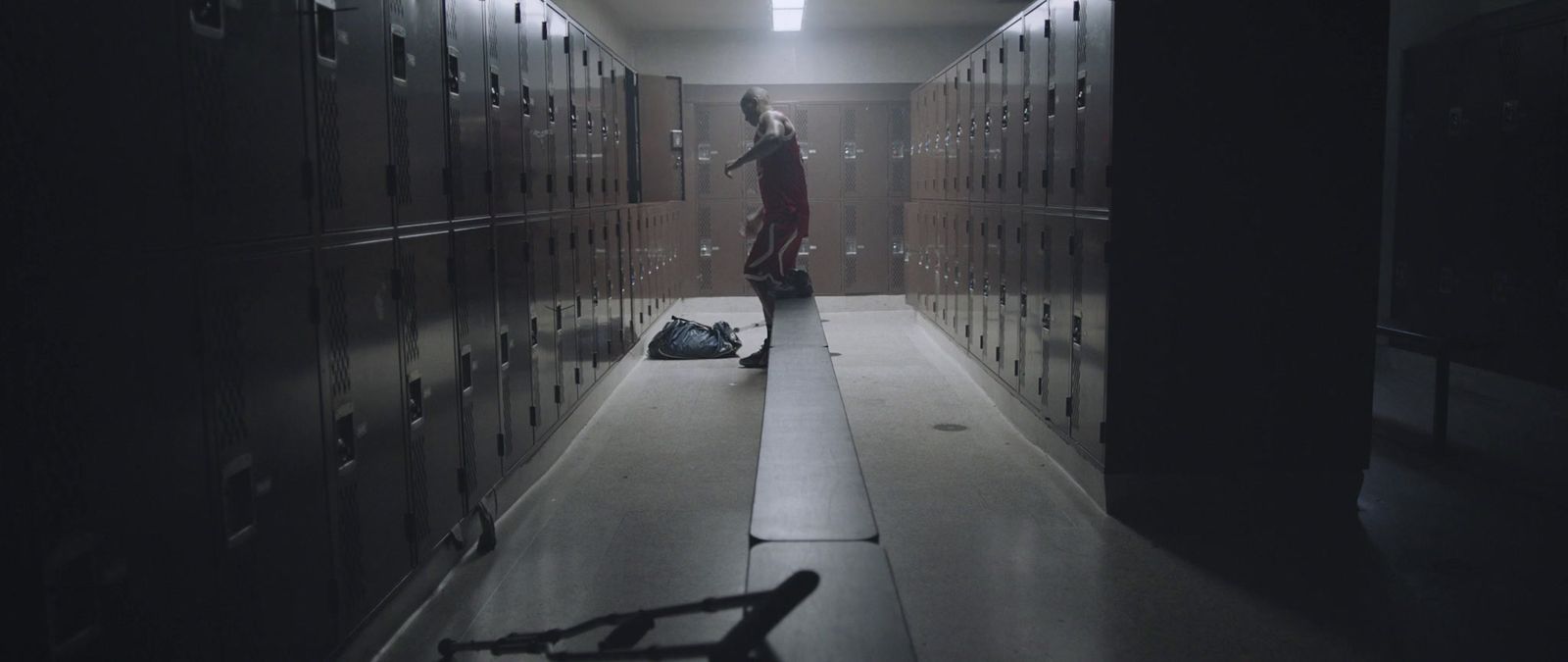 a man standing in a hallway next to a bunch of lockers