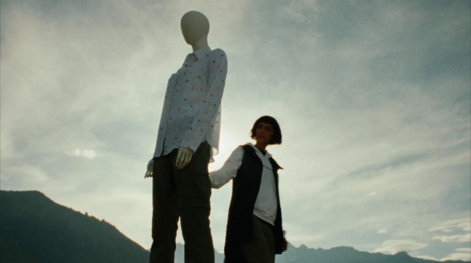 a woman standing next to a mannequin holding hands