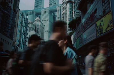 a group of people walking down a street next to tall buildings