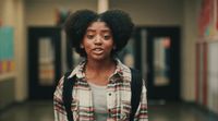 a woman with an afro standing in a hallway