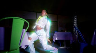 a woman in a white suit dancing in a dark room