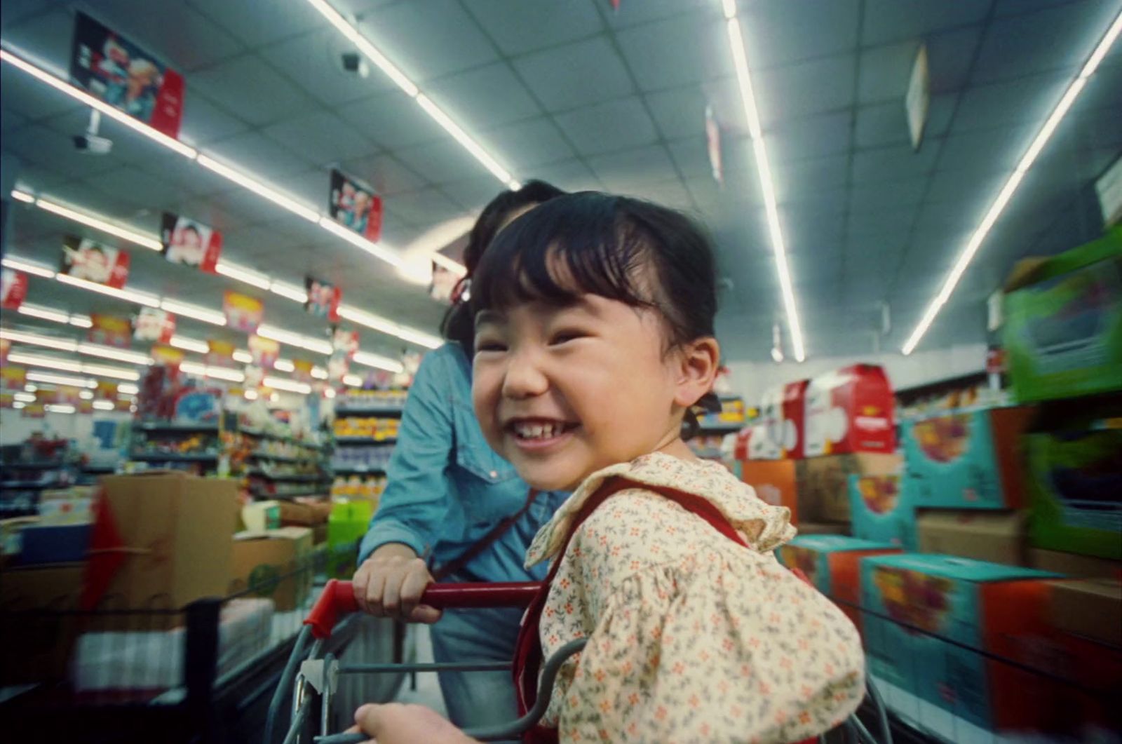 a little girl riding a shopping cart in a store