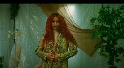 a woman with red hair standing in front of a curtain