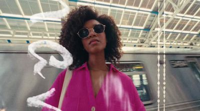 a woman in a pink shirt standing in front of a train