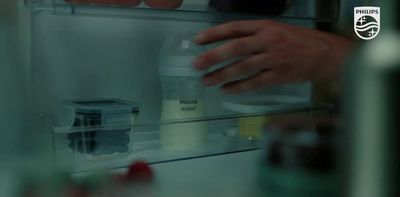 a person holding a bottle in front of a refrigerator