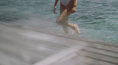 a woman in a white bathing suit walking out of the water