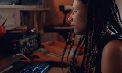 a woman with dreadlocks sitting in front of a keyboard