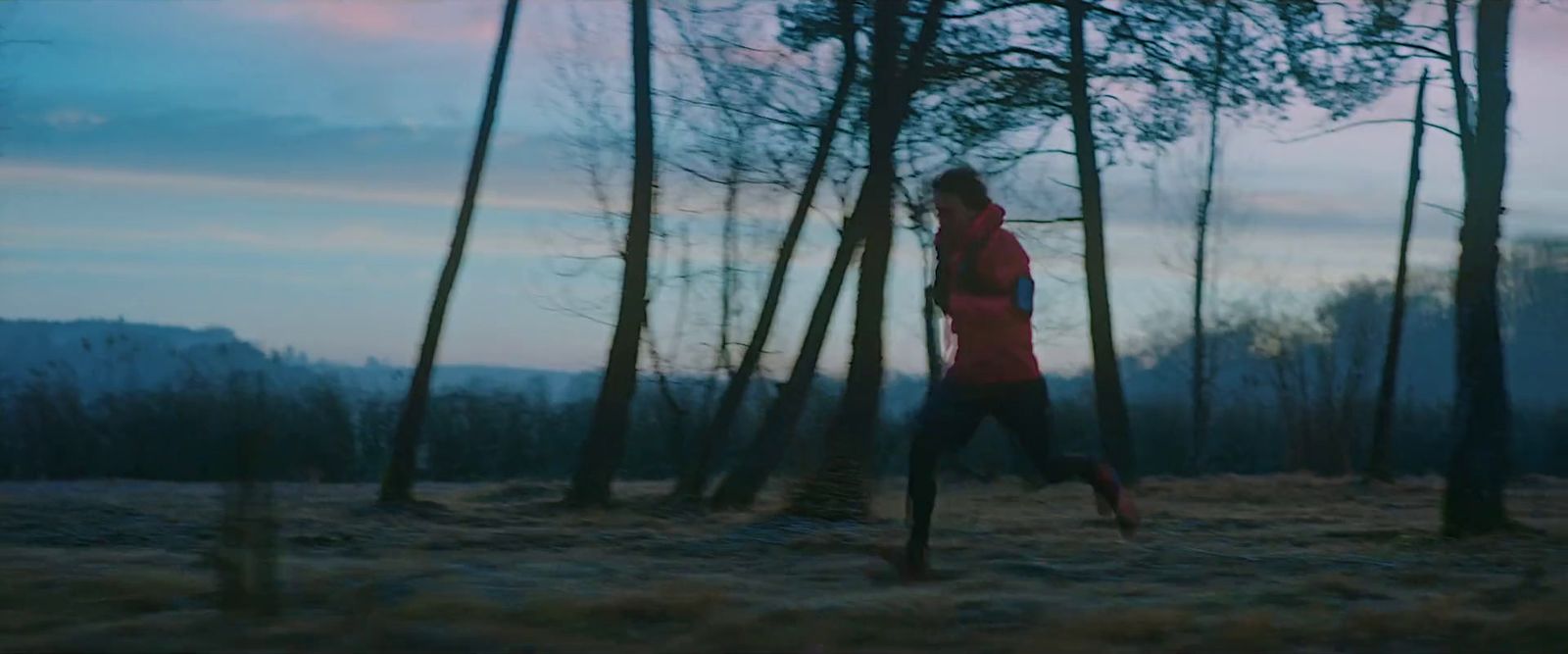 a woman running through a forest at dusk