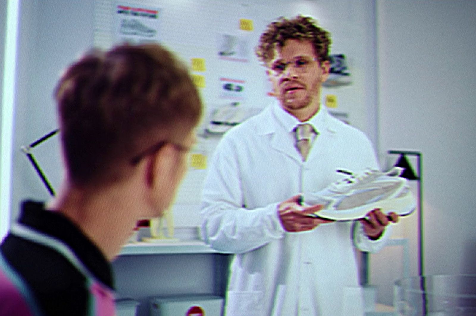 a man in a lab coat holding a tennis shoe