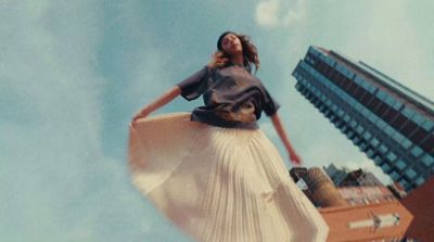 a woman in a white pleated skirt flying through the air