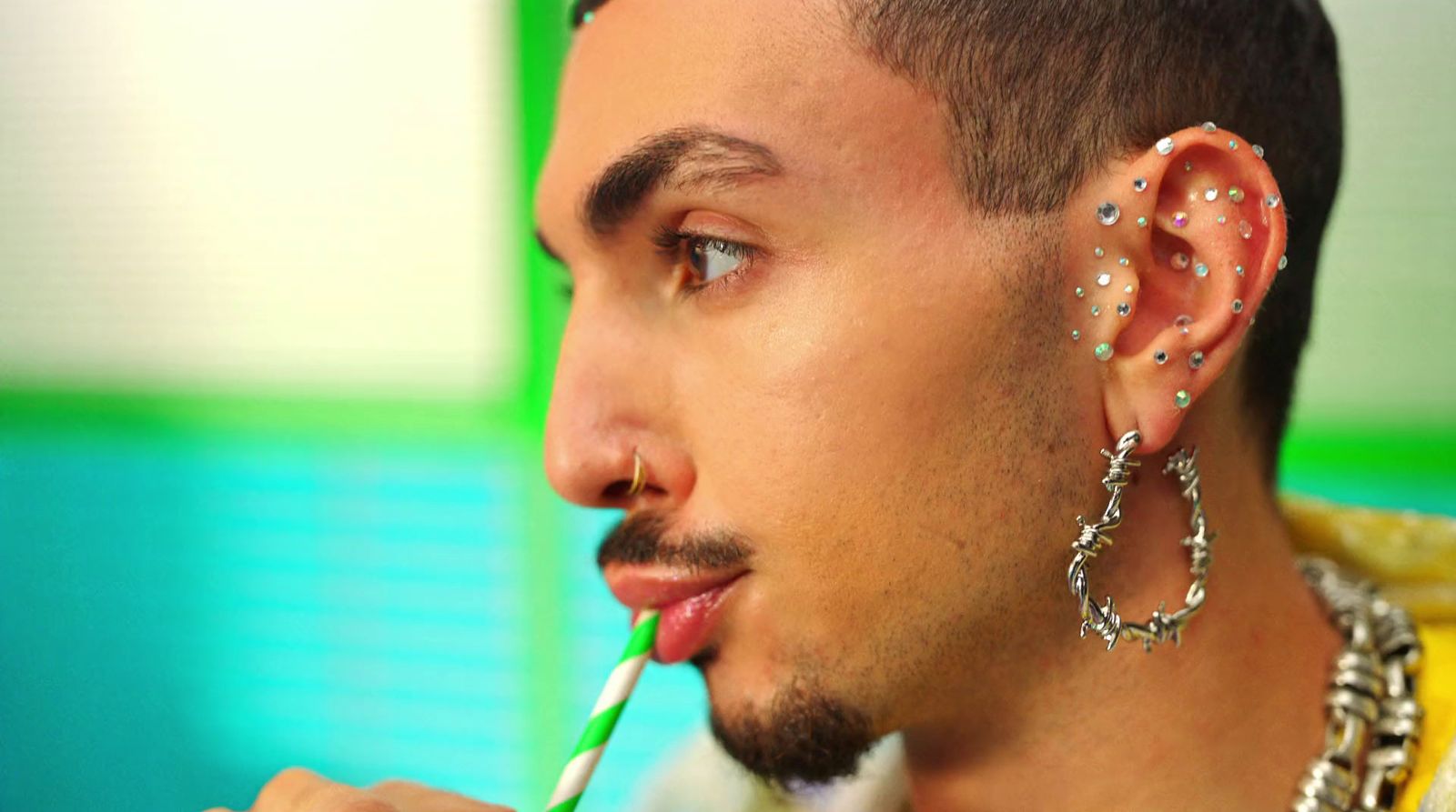 a man with piercings on his ears drinking a drink