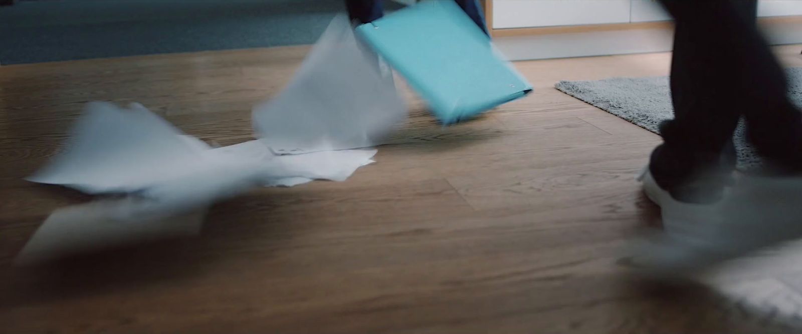 a person walking on a wooden floor with a pair of shoes