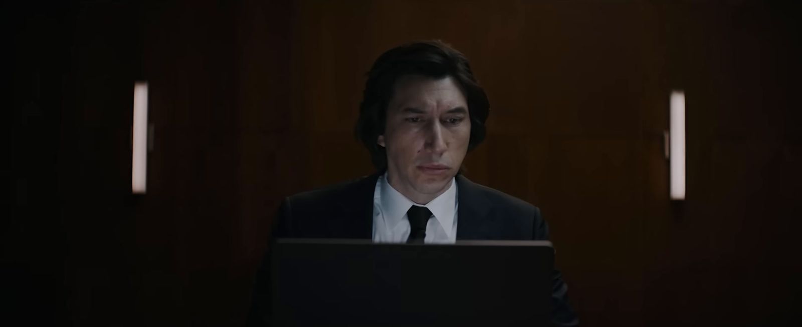 a man in a suit and tie looking at a laptop