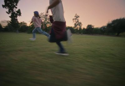 a couple of people that are running in the grass