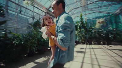 a man holding a little girl in a greenhouse