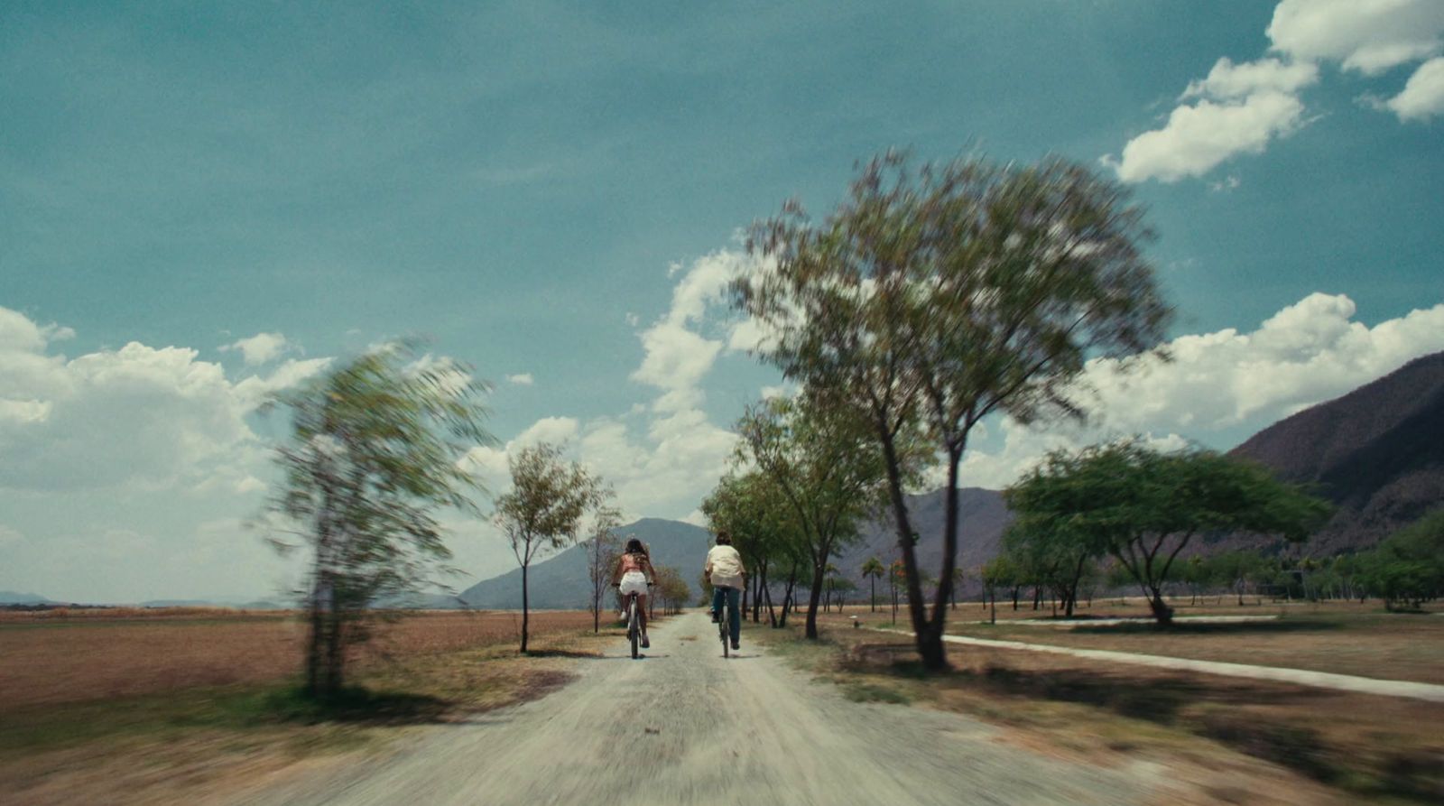 a man riding a bike down a dirt road