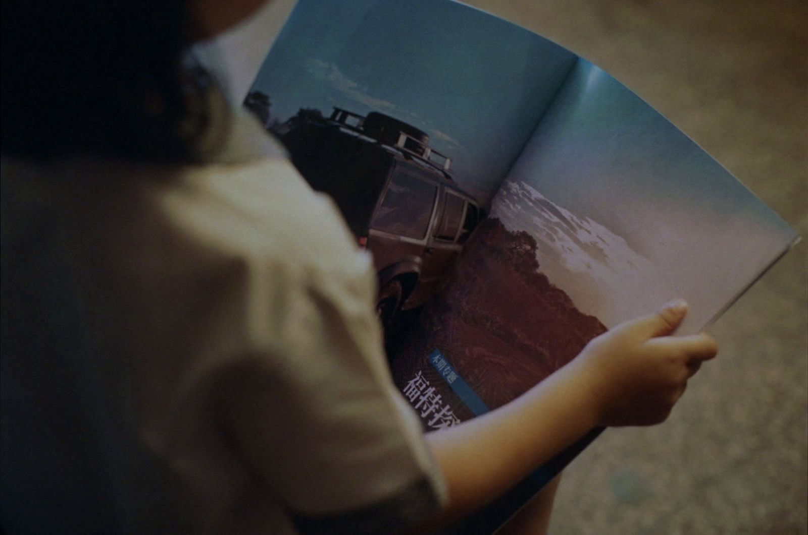 a person holding a book with a picture of a car on it