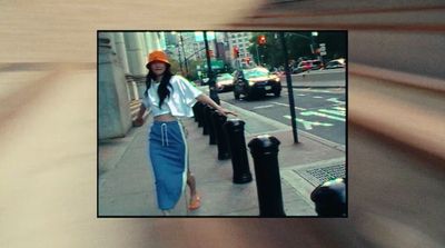 a woman walking down a street next to tall buildings