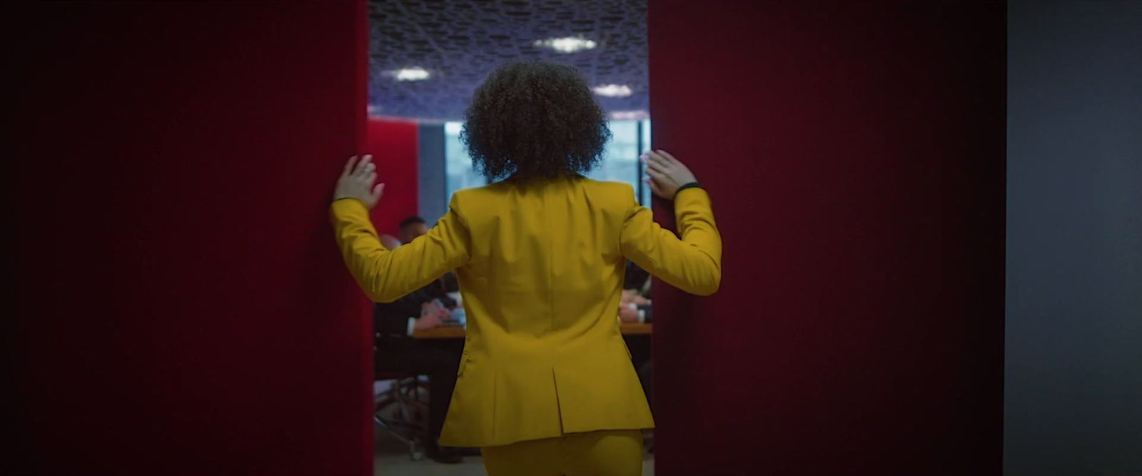 a woman in a yellow suit standing in front of a mirror