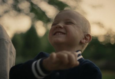 a young boy is smiling and holding his hands together