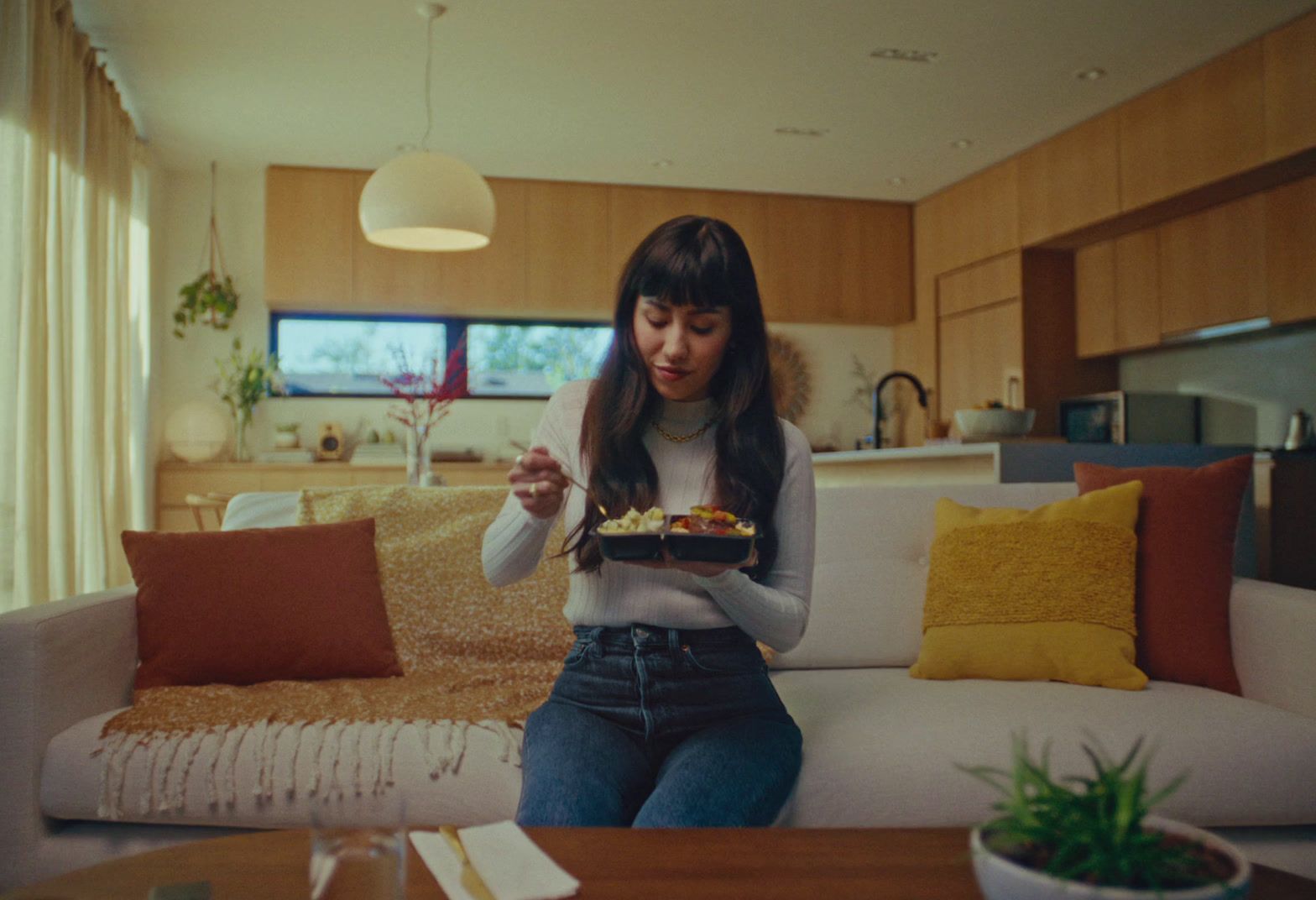 a woman sitting on a couch holding a plate of food