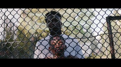 a man standing behind a chain link fence