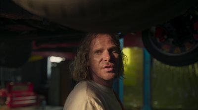 a man with long hair standing in a garage