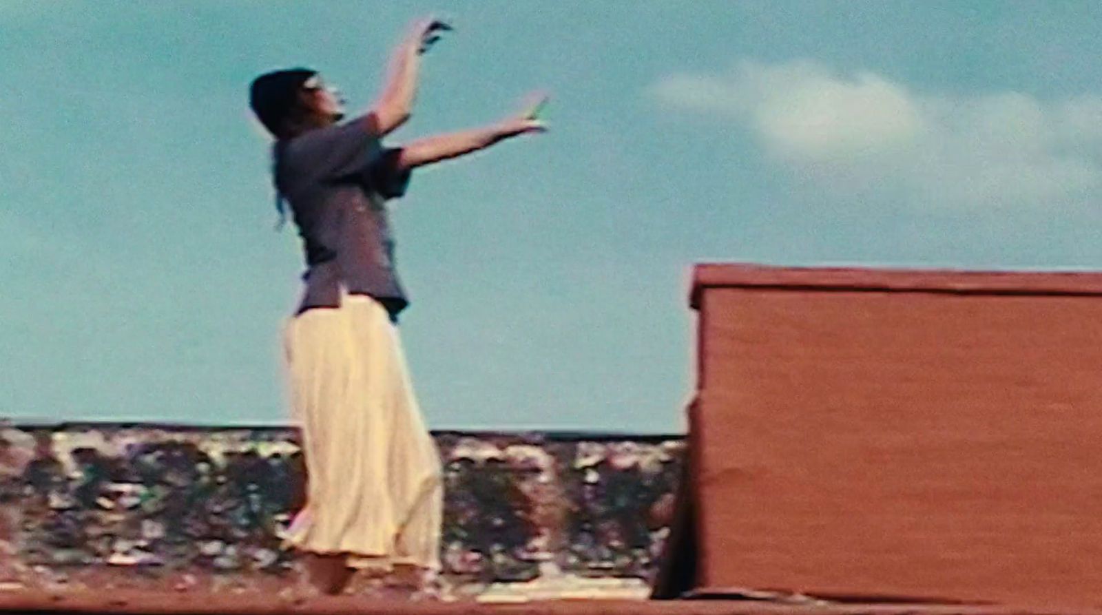 a man standing on top of a roof reaching up to catch a frisbee