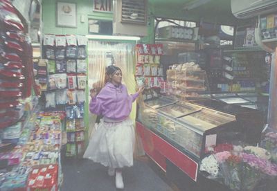 a woman standing in front of a store filled with food