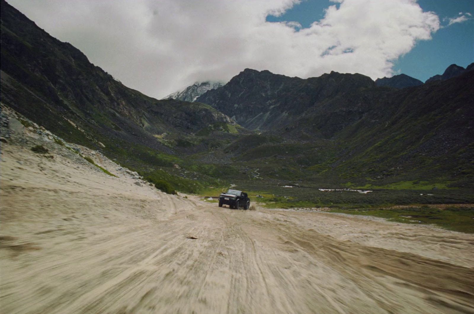 a truck driving down a dirt road in the mountains