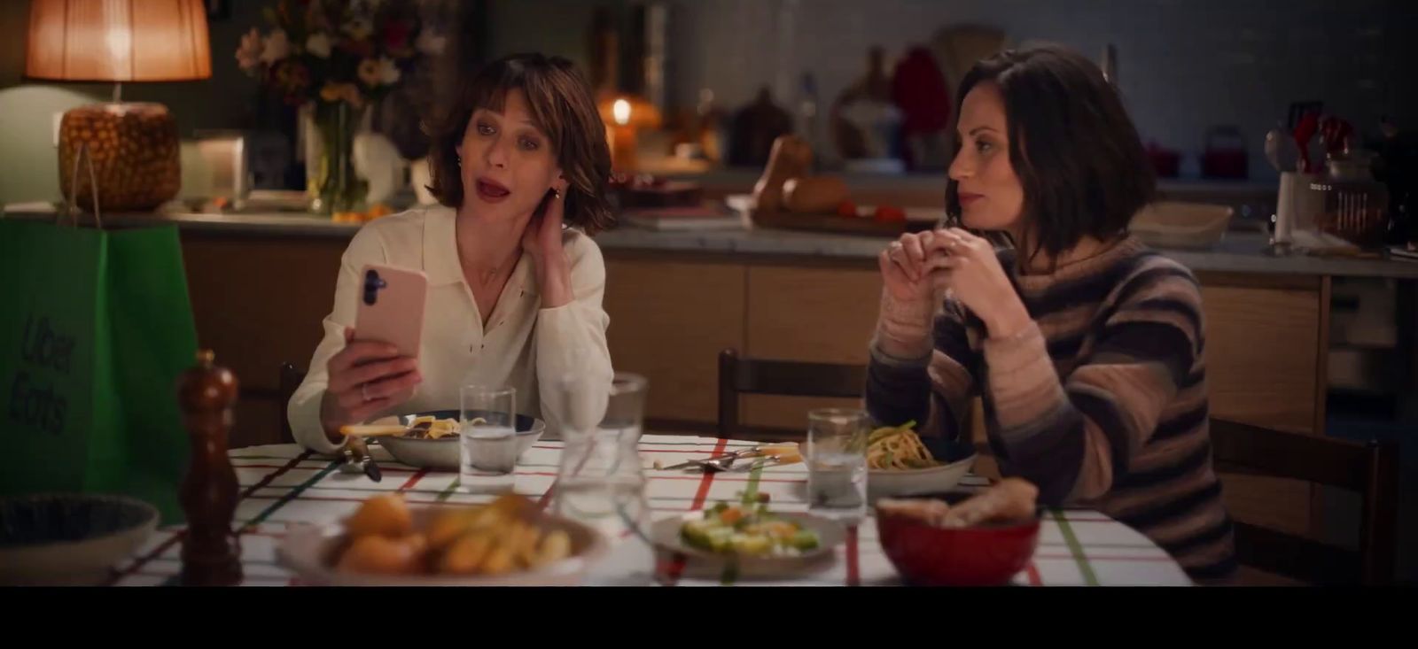 two women sitting at a table with food in front of them