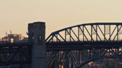 an airplane flying over a bridge with a city in the background