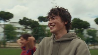 a man in a gray hoodie smiles at the camera