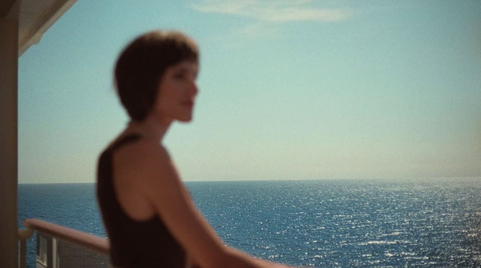 a woman standing on a balcony overlooking the ocean